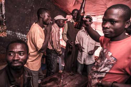 Village de Muchanga, zone d’extraction minière illicite, Kolwezi, province du Katanga, RDC. A la sortie du travail, les creuseurs se retrouvent pour se détendre. La vie sociale s'organise autour des carrières.
